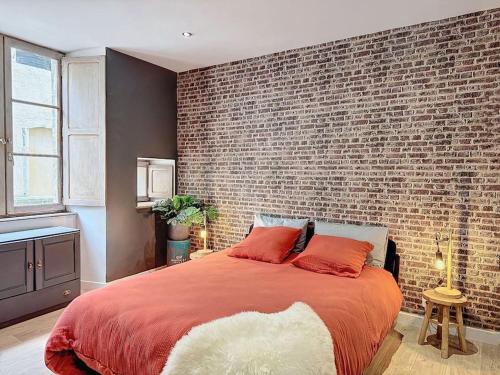 a bedroom with a brick wall and a large bed at Studio Evasion Ardéchoise in Villeneuve-de-Berg