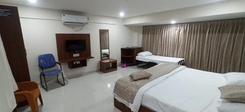 Habitación de hotel con 1 cama, TV y 1 dormitorio. en Kuber Residency en Tirupati