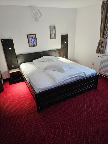 a large bed in a bedroom with a red carpet at Pensiunea Miruna in Moieciu de Jos