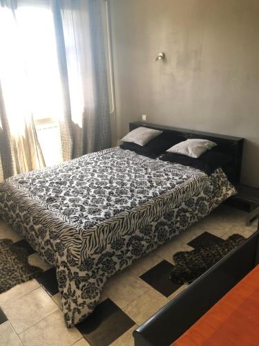 un letto con piumone bianco e nero in una camera da letto di Laila a Creil