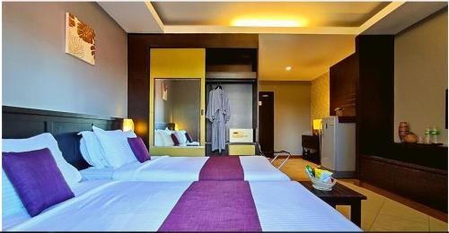 a bedroom with a large white bed with purple pillows at Gazebo Resort, Pattaya in Pattaya