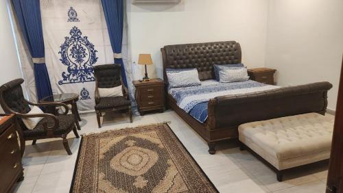 a bedroom with a bed and a couch and chairs at Modern luxury home located in centre of Islamabad in Islamabad