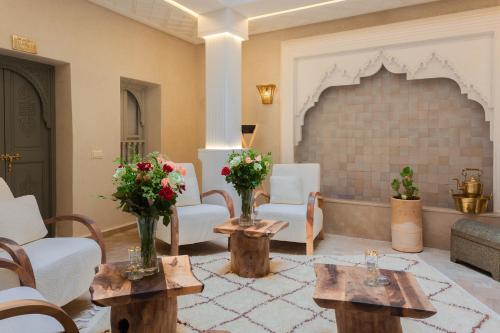 a living room with two tables and a fireplace at Riad Luxe Nomade Marrakech & Spa in Marrakech