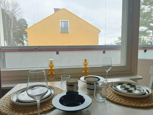 einen Tisch mit Tellern und Weingläsern sowie ein Fenster in der Unterkunft Studio sairaala in Joensuu