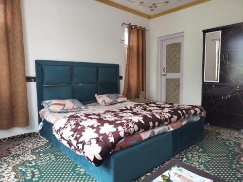 a bedroom with a bed with a blue headboard at Elizabeth paying guest house Tangmarg gulmarg in Gulmarg