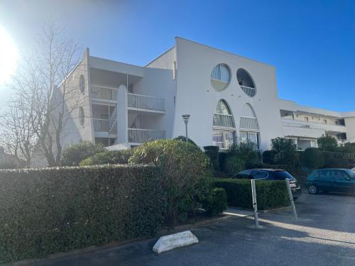 un bâtiment blanc avec des voitures garées dans un parking dans l'établissement Studio à 100 m de la mer, à La Grande Motte