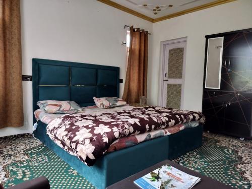 a bedroom with a bed with a blue headboard and a table at Elizabeth paying guest house Tangmarg gulmarg in Gulmarg