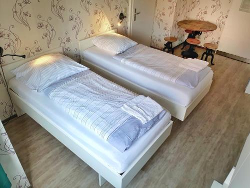 two twin beds in a room with a table at Aparthotel B & L in Bremen
