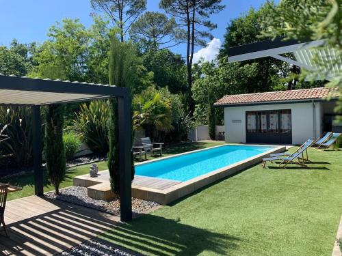 une cour arrière avec une piscine et une maison dans l'établissement Grande villa familiale près du Bassin - 180m2, à Andernos-les-Bains