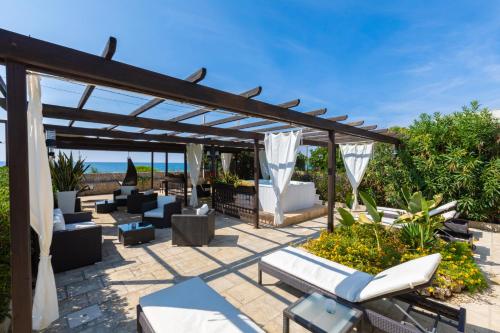 a patio with couches and chairs under a pergola at La Giara Resort in Torre San Giovanni Ugento