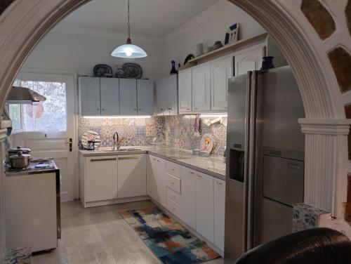 a kitchen with white cabinets and a stainless steel refrigerator at Corfu Airport Flat in Corfu Town