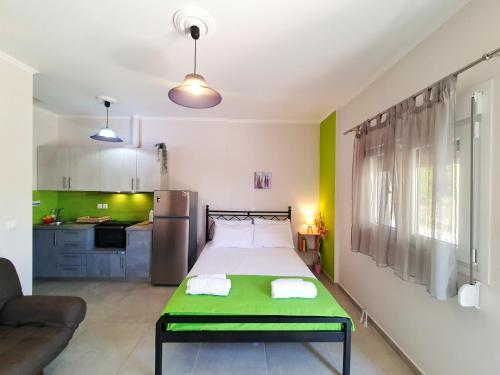a bedroom with a green bed and a kitchen at Green Studio Nidri in Nydri