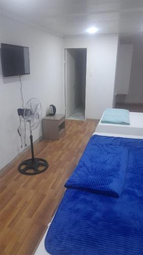 Schlafzimmer mit einem Bett mit blauer Bettwäsche und einem Ventilator in der Unterkunft HOTEL JIMENA in Iquique
