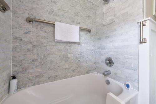 a white bath tub in a bathroom with a tile wall at Garden Getaway - Walking Distance to downtown Douglas - Cute Home! in Douglas