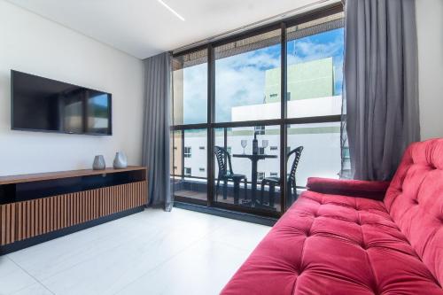 a living room with a red couch and a large window at Unity #421 - Praia de Cabo branco por Carpediem in Penha