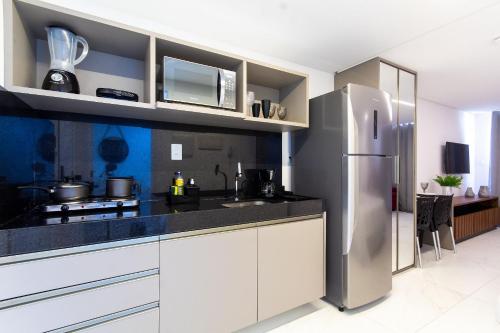 a kitchen with white cabinets and a stainless steel refrigerator at Unity #421 - Praia de Cabo branco por Carpediem in Penha