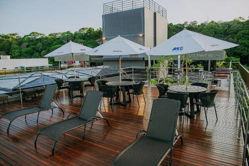 a deck with tables and chairs and umbrellas at Unity #421 - Praia de Cabo branco por Carpediem in Penha