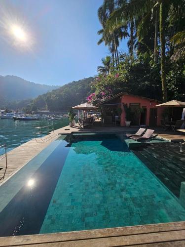a large swimming pool next to a body of water at Pousada e Mergulho Jamanta in Angra dos Reis