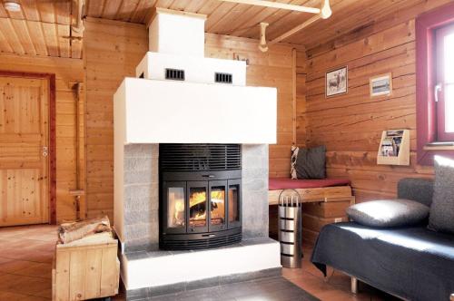 a living room with a fireplace in a log cabin at Gemütliches neu erbautes Blockhaus auf Berghof mit Sauna und Kamin in Galåbodarna