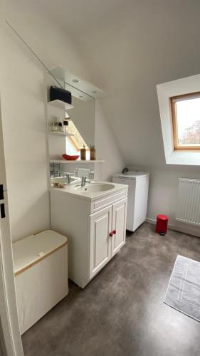 une salle de bain blanche avec un lavabo et un miroir dans l'établissement Très beau T3 proche plage, à Bénodet