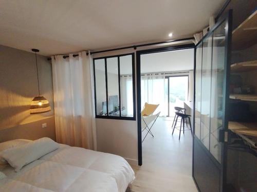 een slaapkamer met een bed en een balkon met een bureau bij T2 neuf, 1 chambre, golf Valcros in La Londe-les-Maures