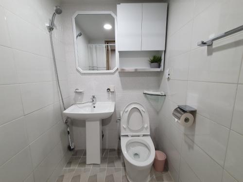 a white bathroom with a toilet and a sink at Hyelang House in Seongnam