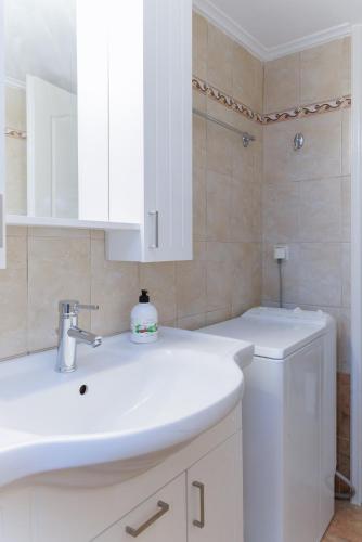 a bathroom with a white sink and a white cabinet at Platsa Seaview Retreat - A Stone-Built Escape in Plátsa