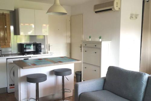 une cuisine avec un comptoir, une chaise et un four micro-ondes dans l'établissement Terrasse ensoleillée et accès à la piscine vue mer, à Vallauris