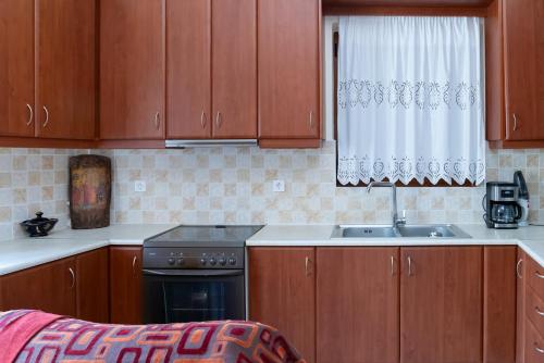 a kitchen with wooden cabinets and a sink at Platsa Seaview Retreat - A Stone-Built Escape in Plátsa
