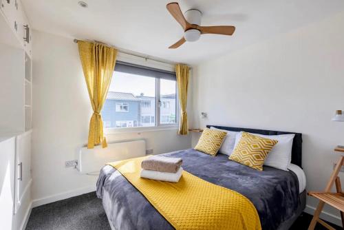 1 dormitorio con 1 cama con manta amarilla y ventana en Beach Woods Coastal Path chalet en Pembrokeshire