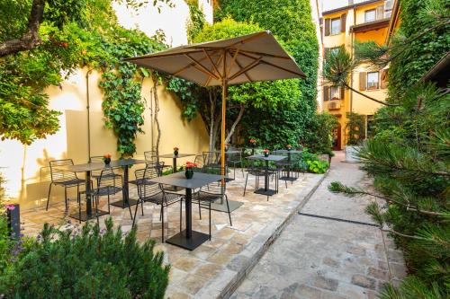 un groupe de tables et de chaises avec un parapluie dans l'établissement Hotel Porta San Mamolo, à Bologne