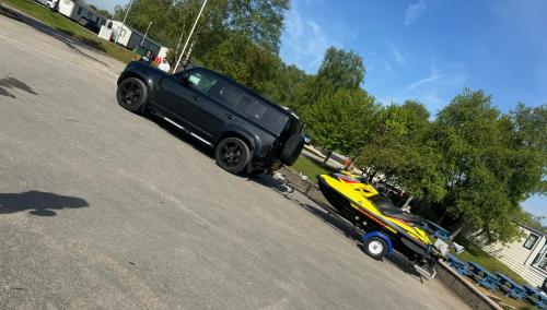a black truck parked next to a colorful car on a street at Lakeside Dorchester Lodge - Hot Tub with Fishing Peg in Tattershall