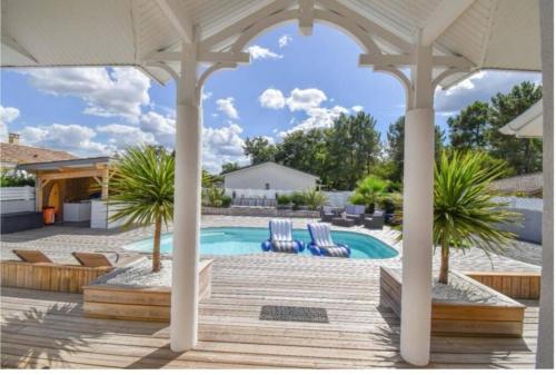 - une piscine avec 2 chaises et un pavillon dans l'établissement Maison proche Océan avec piscine, à Saint-Médard-en-Jalles