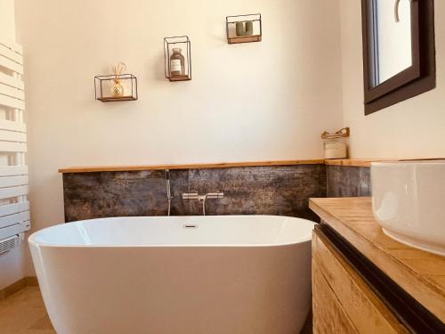 La salle de bains est pourvue d'une baignoire blanche et d'un lavabo. dans l'établissement Gite La Madeleine du Luberon., à Lioux