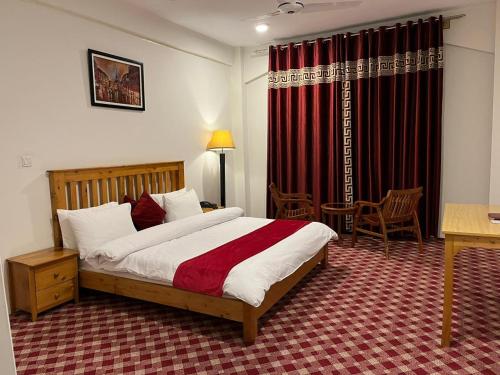 1 dormitorio con cama, mesa y escritorio en Hispar Hotel Skardu, en Skardu