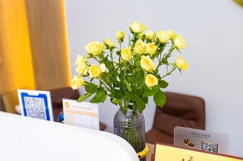 a vase filled with yellow flowers on a table at Tropic Bloom Hotel in Móng Cái