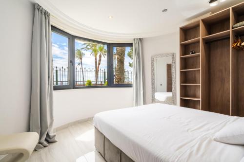 a bedroom with a large bed and a large window at Puerto Banús Beach Apartments in Marbella