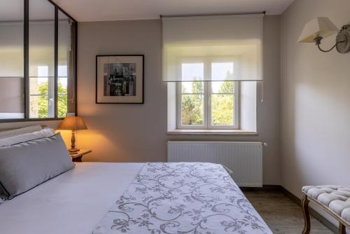 a bedroom with a large bed and two windows at Château La Gravière in Vertheuil-en-Médoc