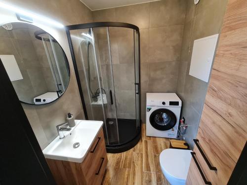 a bathroom with a shower and a sink and a washing machine at Pole Lawendowe Sielsko - domek na polu in Pawłów