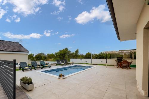 una piscina en un patio con sillas y un patio en Villa Shaula 2, en Bilice