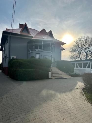 a large white house with the sun setting behind it at Zajazd Restauracja Derby in Błonie