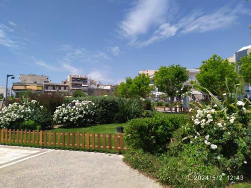 a garden with white flowers and a wooden fence at On the METRO station of Korydallos in Piraeus