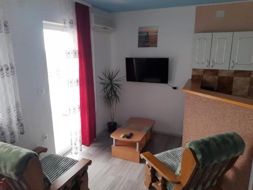 een woonkamer met een televisie en een tafel en stoelen bij Apartmani Kalajevo in Crikvenica