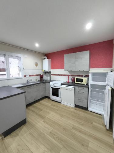 - une cuisine avec des appareils blancs et un mur rouge dans l'établissement Maison au pied de la vielle ville du Puy en Velay, au Puy-en-Velay