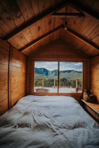 a large bed in a wooden room with a large window at Cioclovina Tribe in Cioclovina