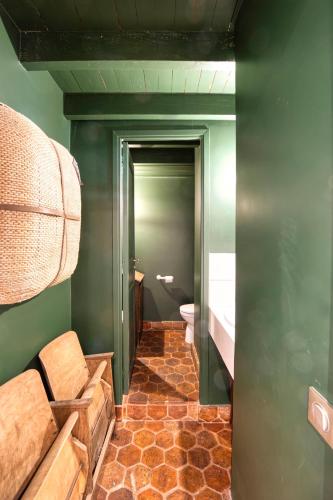 La salle de bains est pourvue de toilettes et de murs verts. dans l'établissement Maison Cèdre, à Boulogne-Billancourt