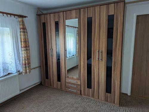 a large wooden cabinet with a mirror in a room at Dvougenerační dům se zahradou in Vimperk