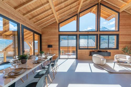 - une salle à manger avec une grande table, des chaises et de grandes fenêtres dans l'établissement Chalet For Friends Luxe et Spa, à Briançon