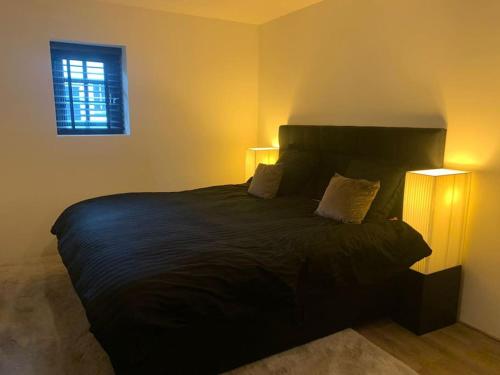 a bedroom with a large black bed with two lamps at tuinhuis in Harmelen