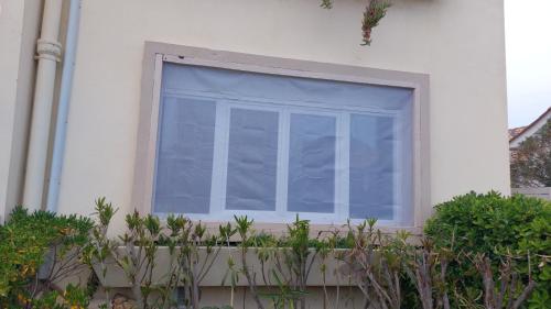 uma janela com uma cortina azul numa casa em Appart T3 50m PLAGE JARDIN PARKING em Palavas-les-Flots